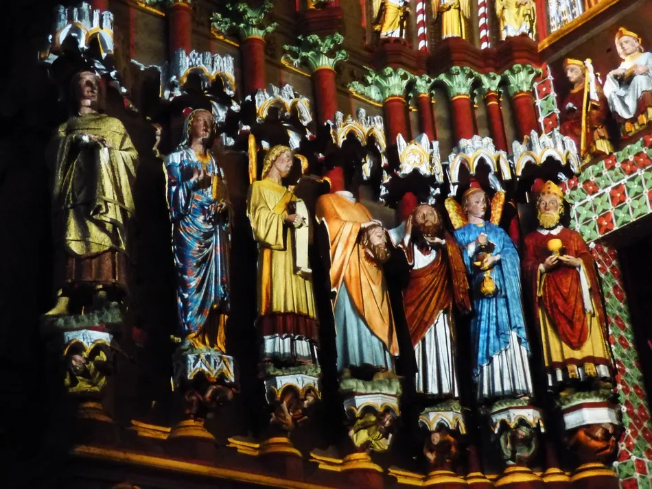 Statues polychromes du portail médiéval de la cathédrale d'Amiens restituées dans leurs couleurs d'origine — figures aux robes bleu, or et rouge devant colonnes vermillon