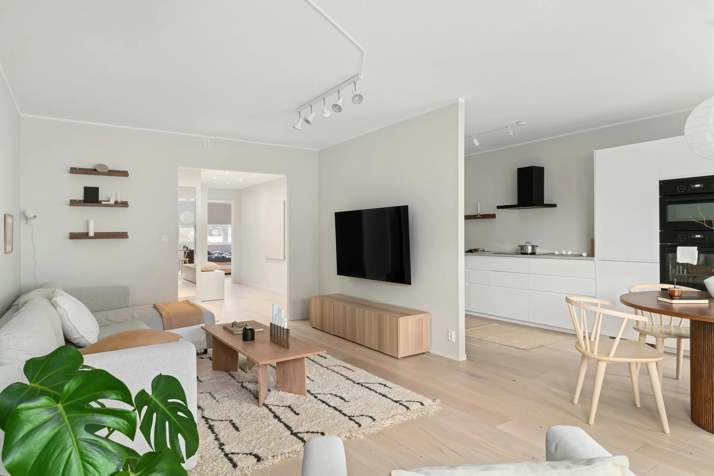 Intérieur d'appartement contemporain aux tons greige — mobilier scandinave épuré, murs blancs, parquet clair et canapé beige, archétype de l'esthétique de location courte durée